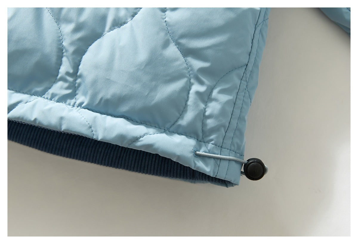 Close-up of the light blue jacket's quilted hem, dark ribbed waistband, and adjustable drawcord toggle.