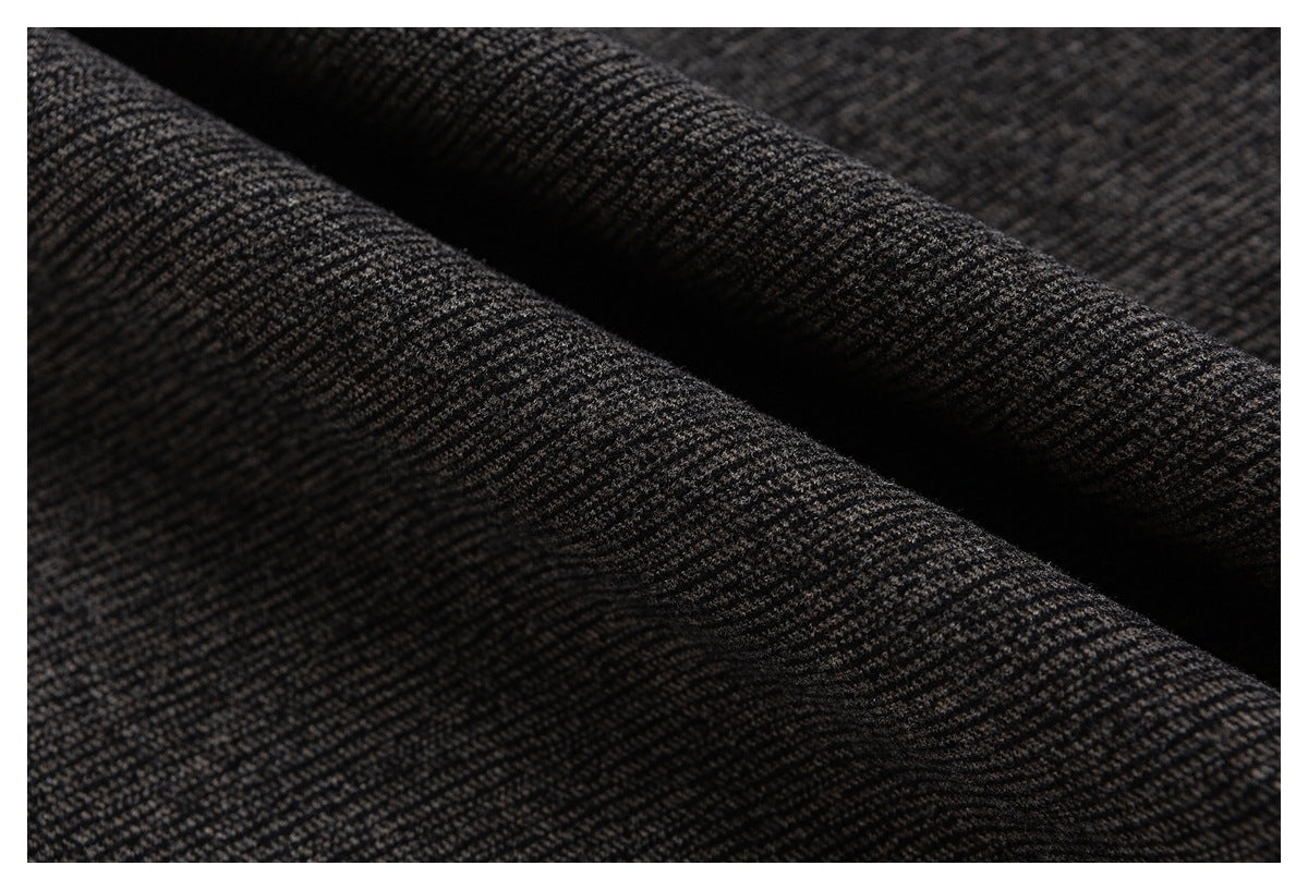 Close-up of dark charcoal fabric with a subtle small-scale woven pattern and deep folds.