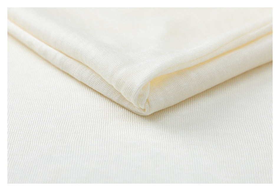 Close-up of folded ivory fabric with a fine, subtly ribbed surface.