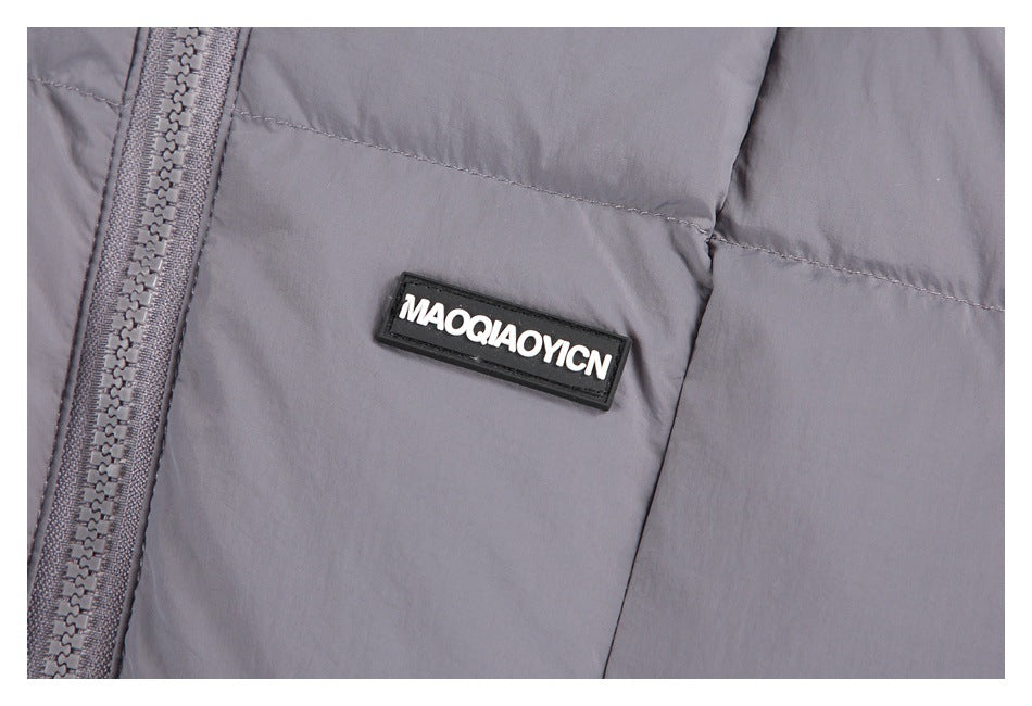 Close-up of a gray puffer jacket's front zipper, quilted panels, and black rectangular chest badge.