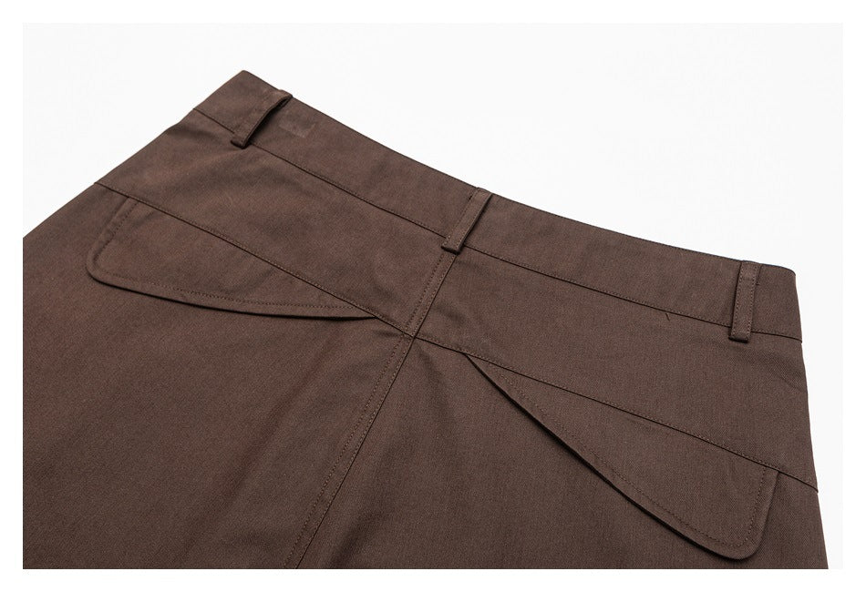 Close-up of brown trousers showing the waistband, belt loops, and curved pocket seams.