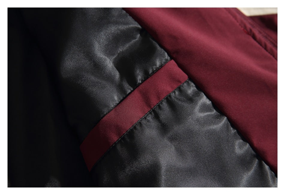 Close-up of black jacket lining with a burgundy fabric strip and stitched seams.