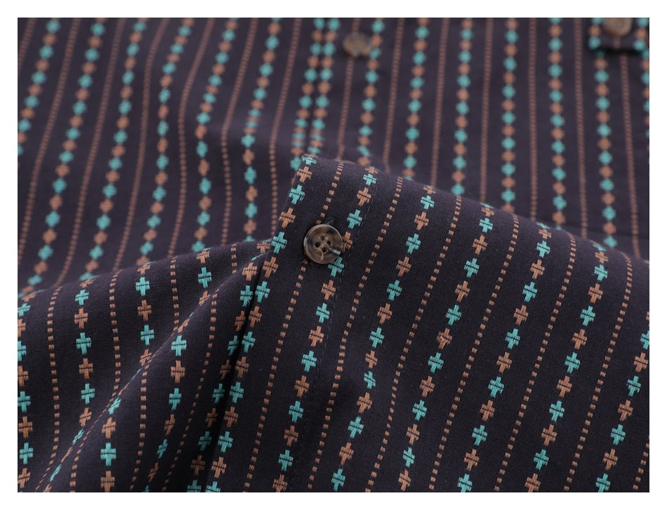 Close-up of a brown button and patterned fabric on the dark shirt.
