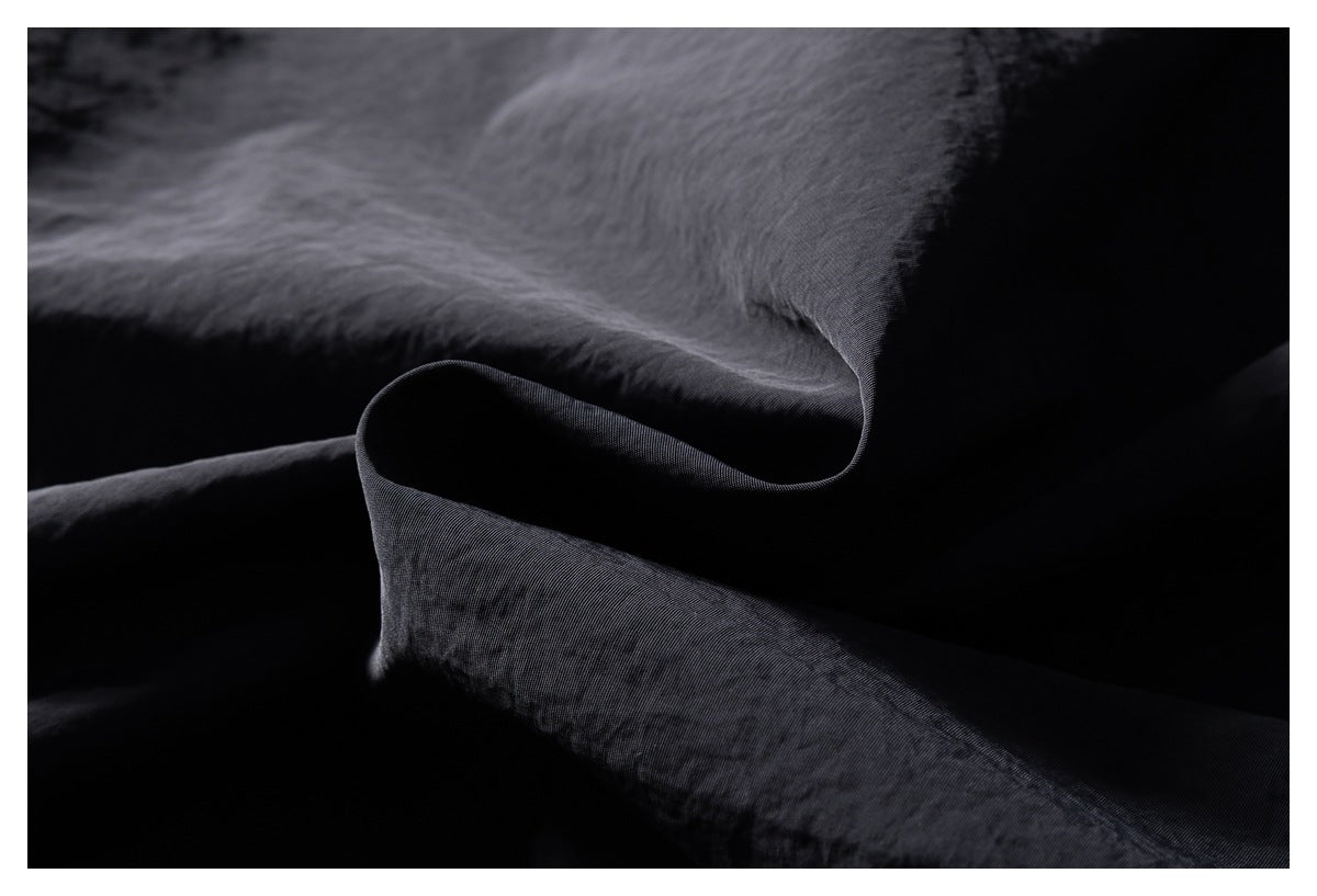 Macro view of dark fabric folds showing its subtle woven texture.