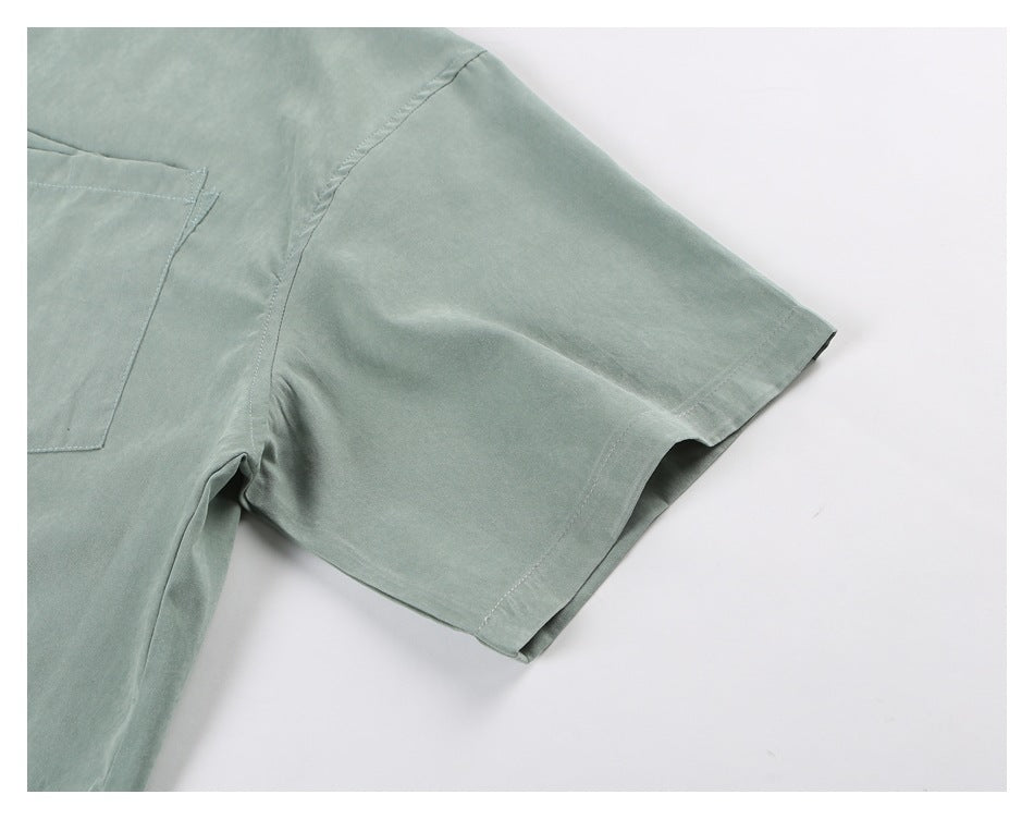 Close-up of the sage-green shirt's short sleeve and stitched hem.