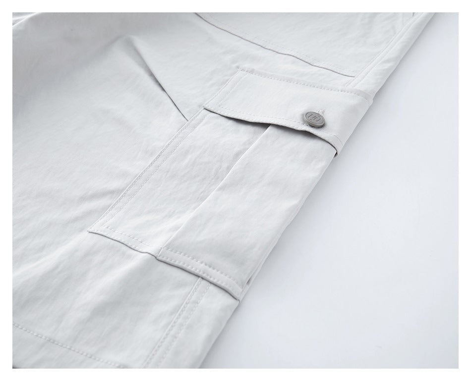 Close-up of white trousers with a large flap pocket secured by a small button.