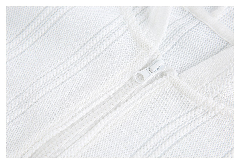 Close-up of a white zipper set into textured white knit fabric.