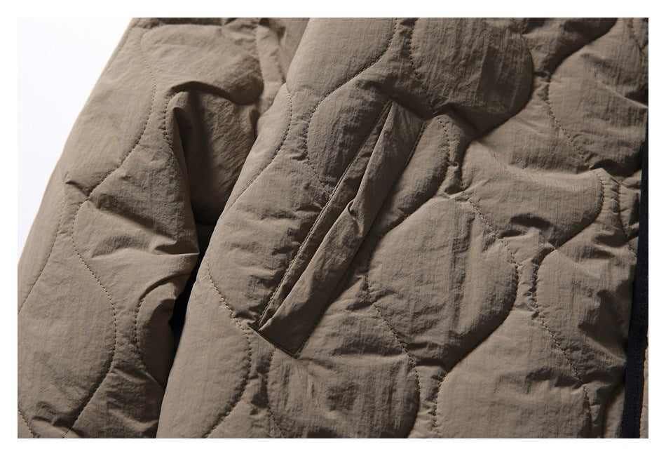 Close-up of an angled pocket on the taupe quilted jacket, with rounded stitched panels.