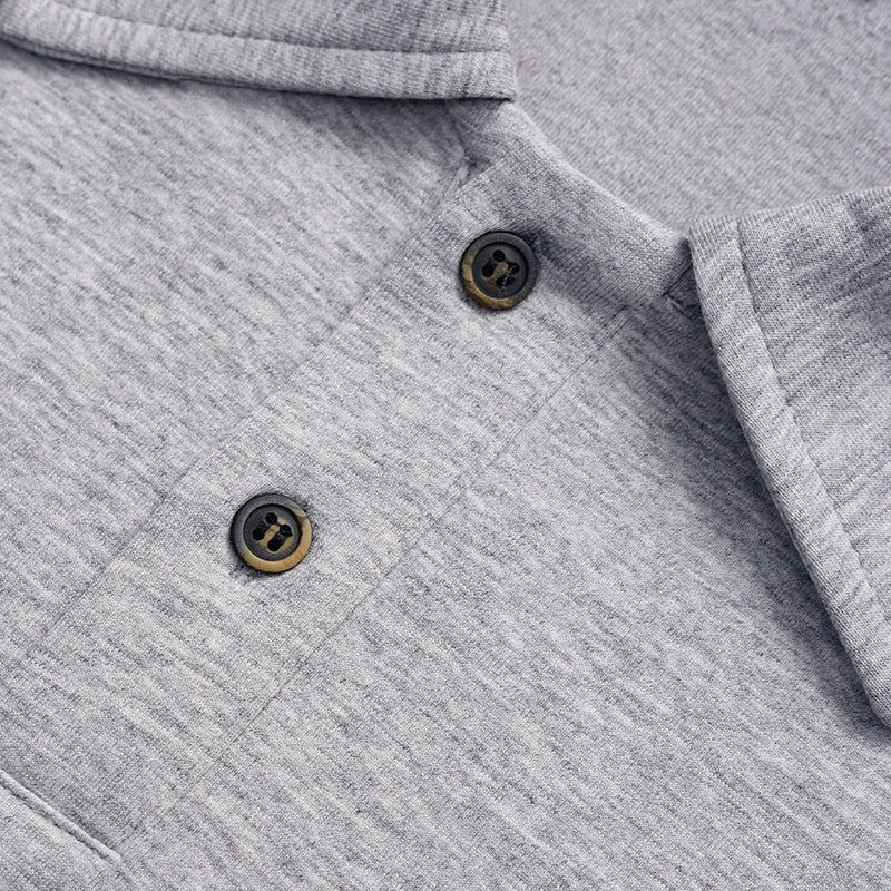 Close-up of two dark buttons and the heather gray polo shirt's collar and placket stitching.