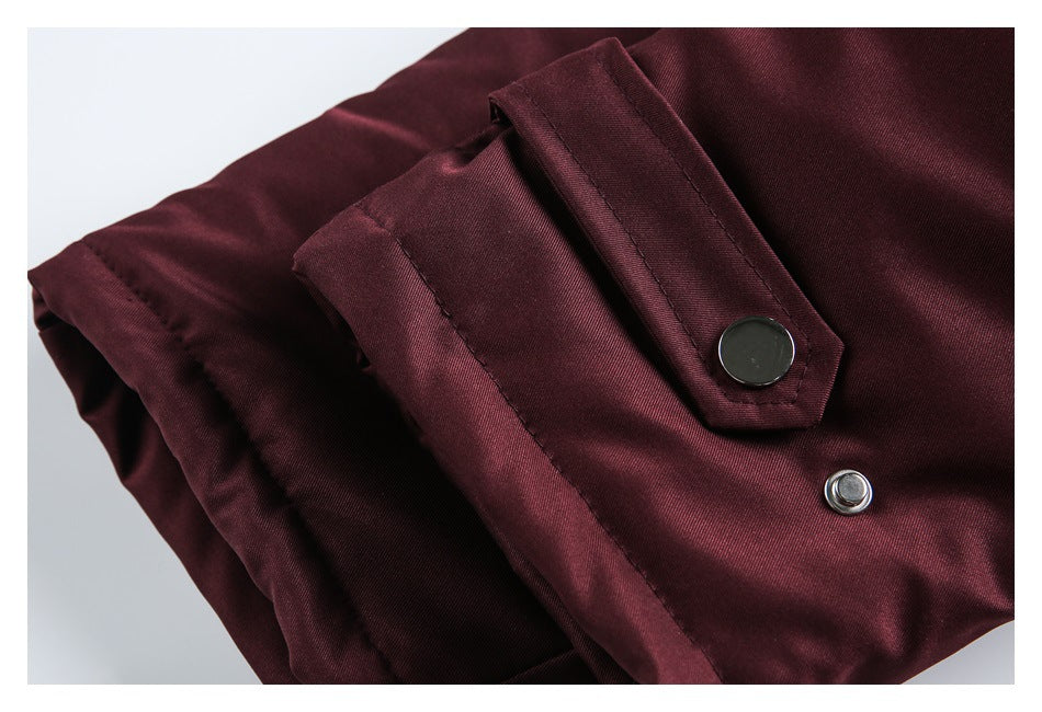 Close-up of a burgundy garment with a stitched snap-button placket and metal fasteners.