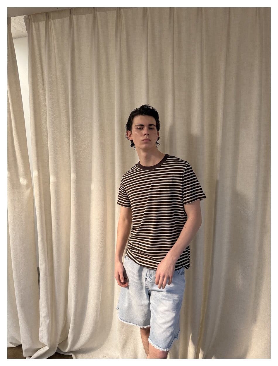 Model wearing a dark brown and cream horizontally striped T-shirt with a brown crew neck.