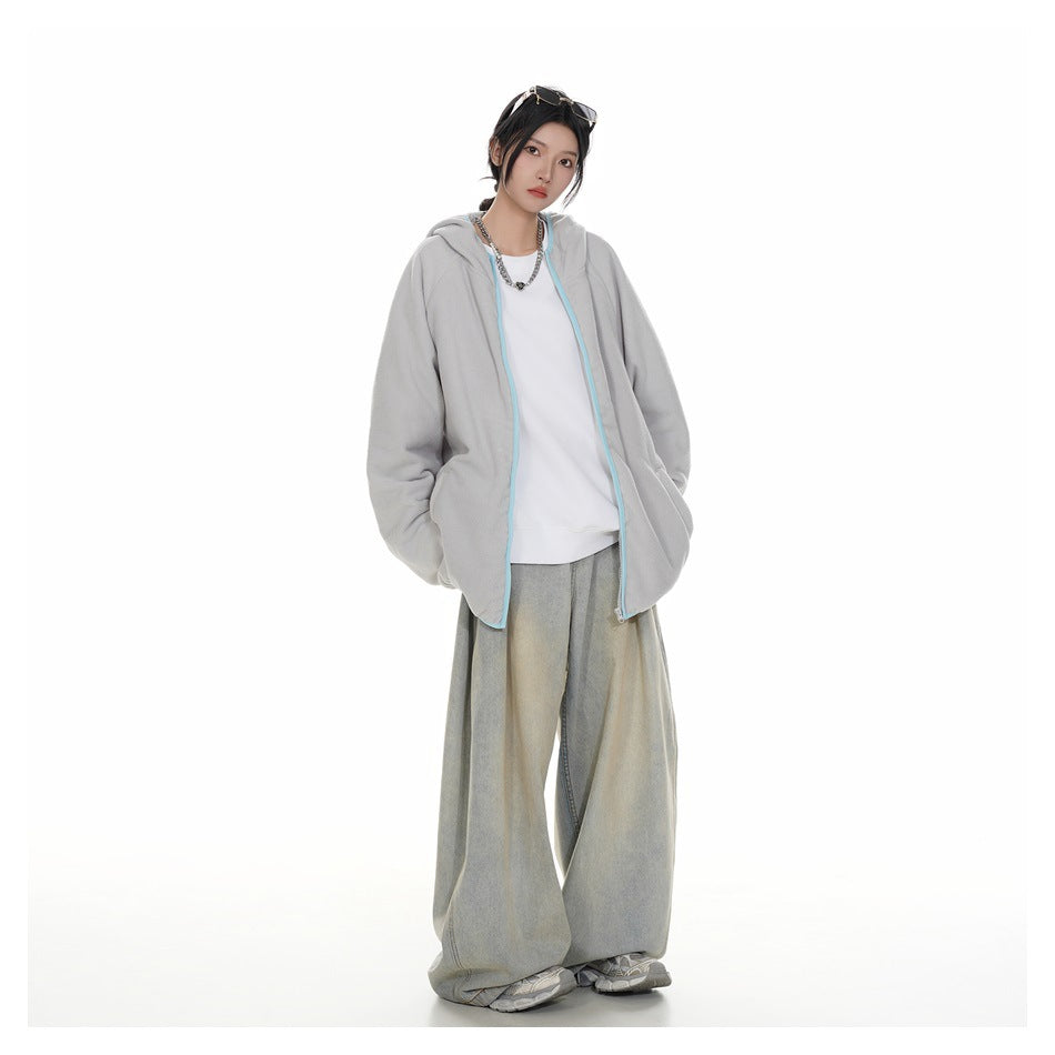 Model wearing a light gray zip-up hooded jacket with pale blue trim, white shirt, and loose gray jeans.