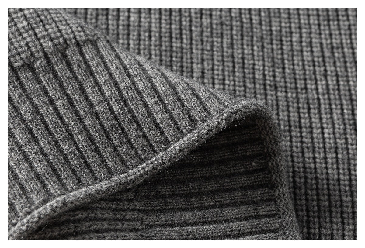 Extreme close-up of a gray sweater's textured knit and ribbed cuff edge.
