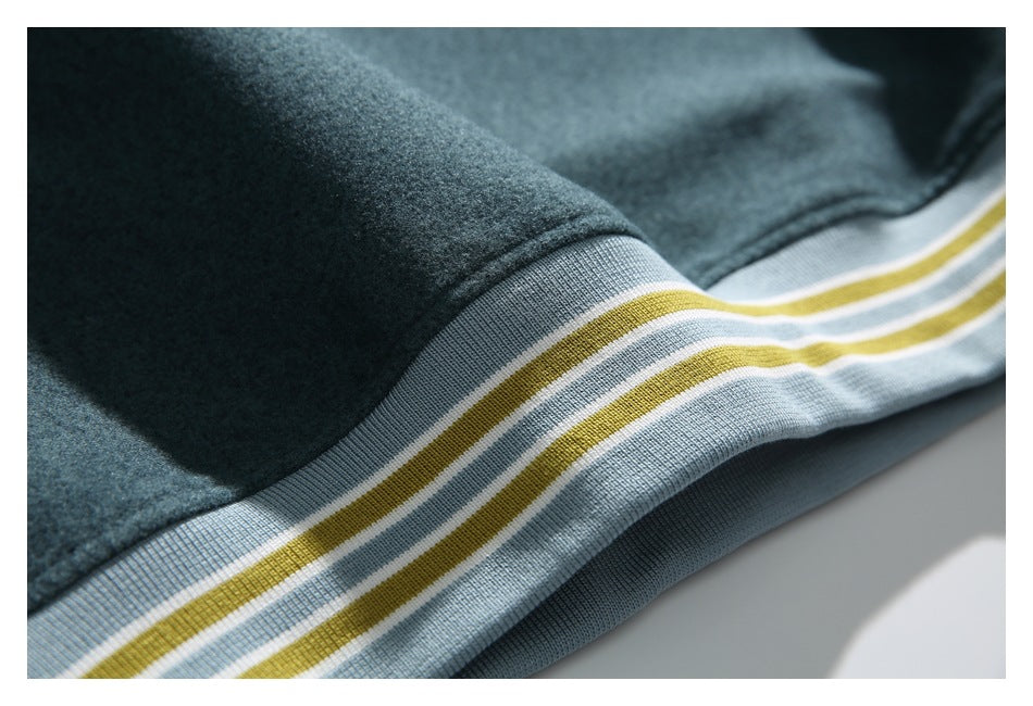 Macro view of dark teal fabric and striped light blue ribbed trim.