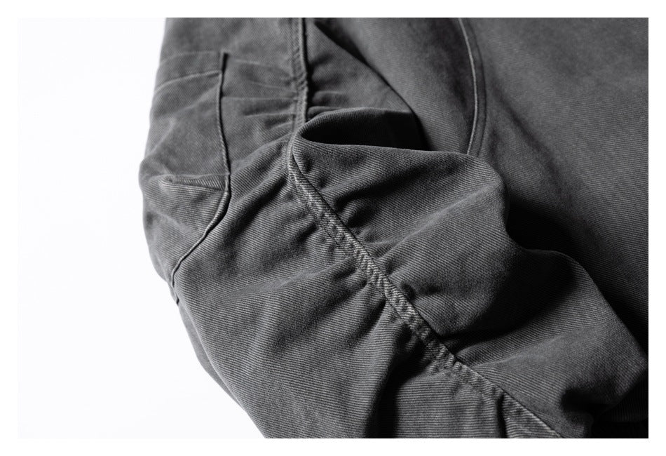 Close-up of a charcoal jacket pocket opening and curved stitched seam.