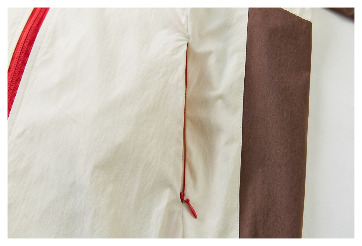 Close-up of a cream garment showing a red main zipper, a concealed red pocket zipper, and a brown side panel.