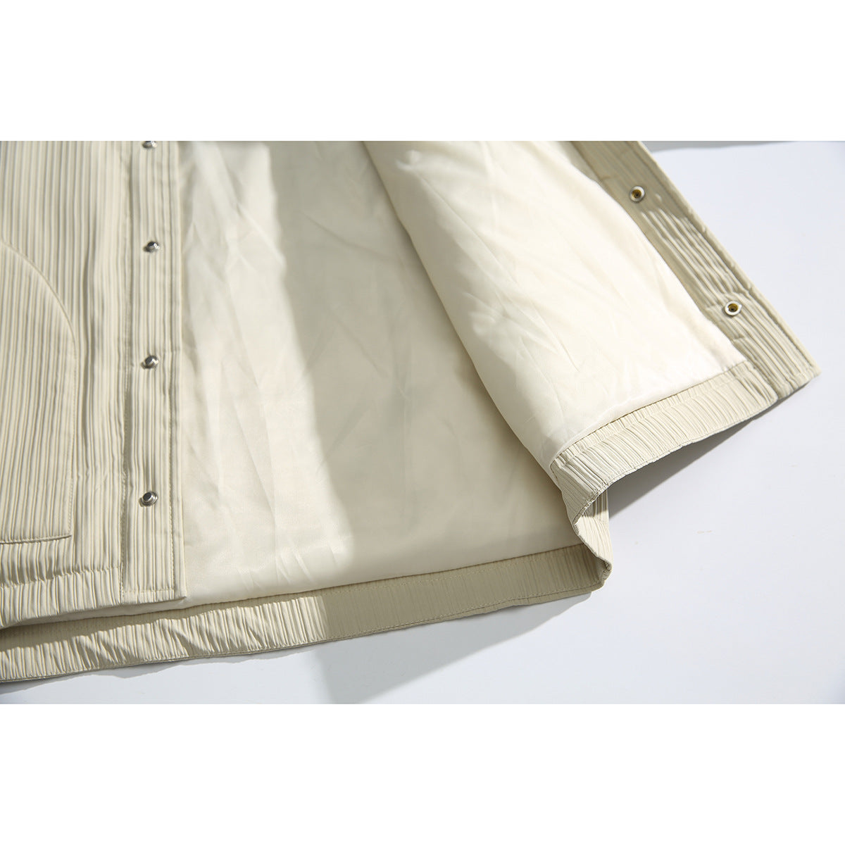 Close-up of the ivory jacket opened to show its light lining, inner seams, and snap closures.