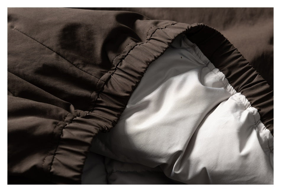 Close-up of a dark garment’s gathered, stitched edge beside smooth white lining.