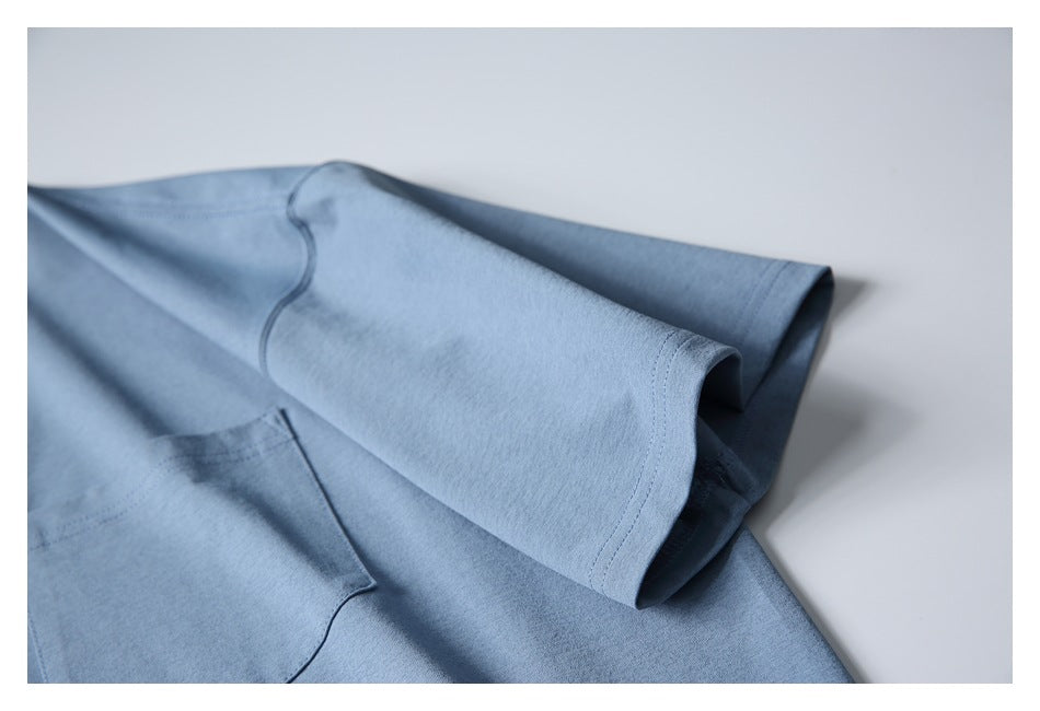 Close-up of the dusty blue T-shirt's short sleeve, showing its stitched hem and seam details.