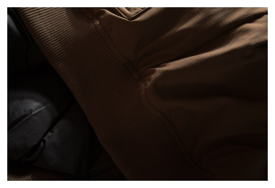 Close-up of a brown garment's wide ribbed band and adjoining stitched fabric.