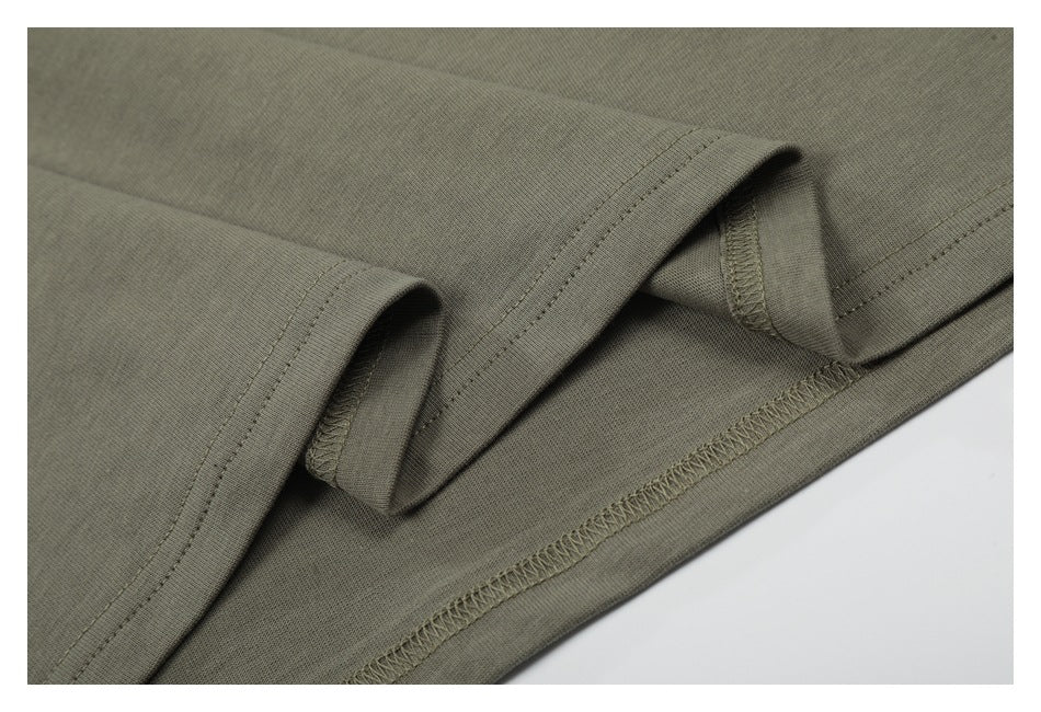 Close-up of the garment's olive-gray hem, showing inner overlock stitching and folded edges.