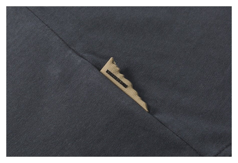 Dark charcoal fabric seam with a narrow tan tab bearing small lettering.