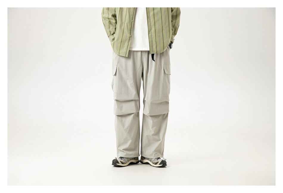 Front view of a model wearing light gray loose cargo pants with oversized thigh pockets and straight legs.