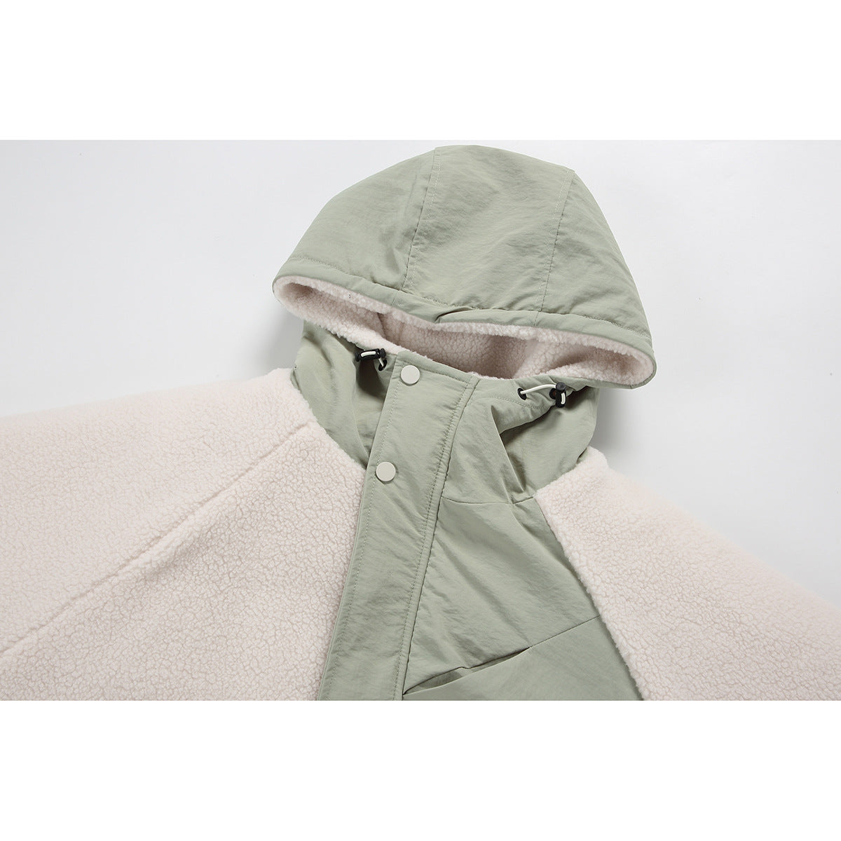 Close-up of a sage-green hood and snap-front panel with cream fleece lining on a color-block jacket.