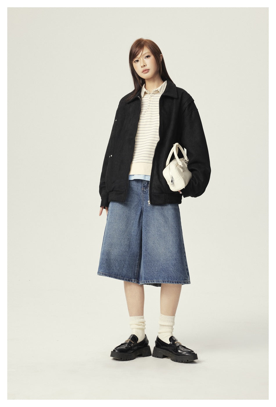 Model wearing an oversized black zip jacket over a striped top and denim midi skirt.