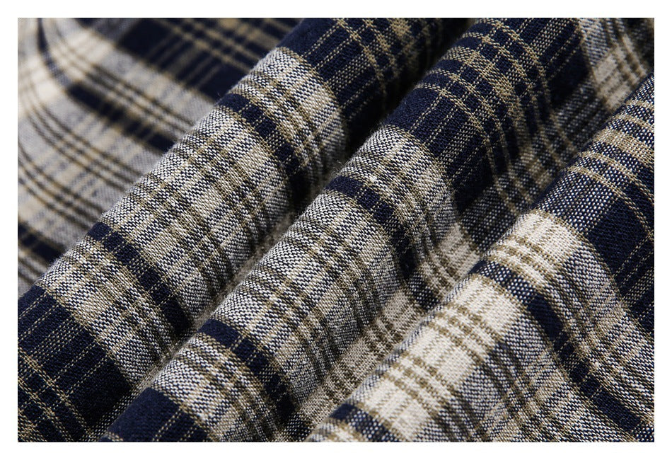 Macro view of textured navy, cream, and tan plaid fabric arranged in soft folds.