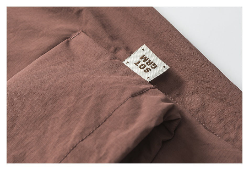 Close-up of mauve-brown garment stitching and a small sewn-in white label.
