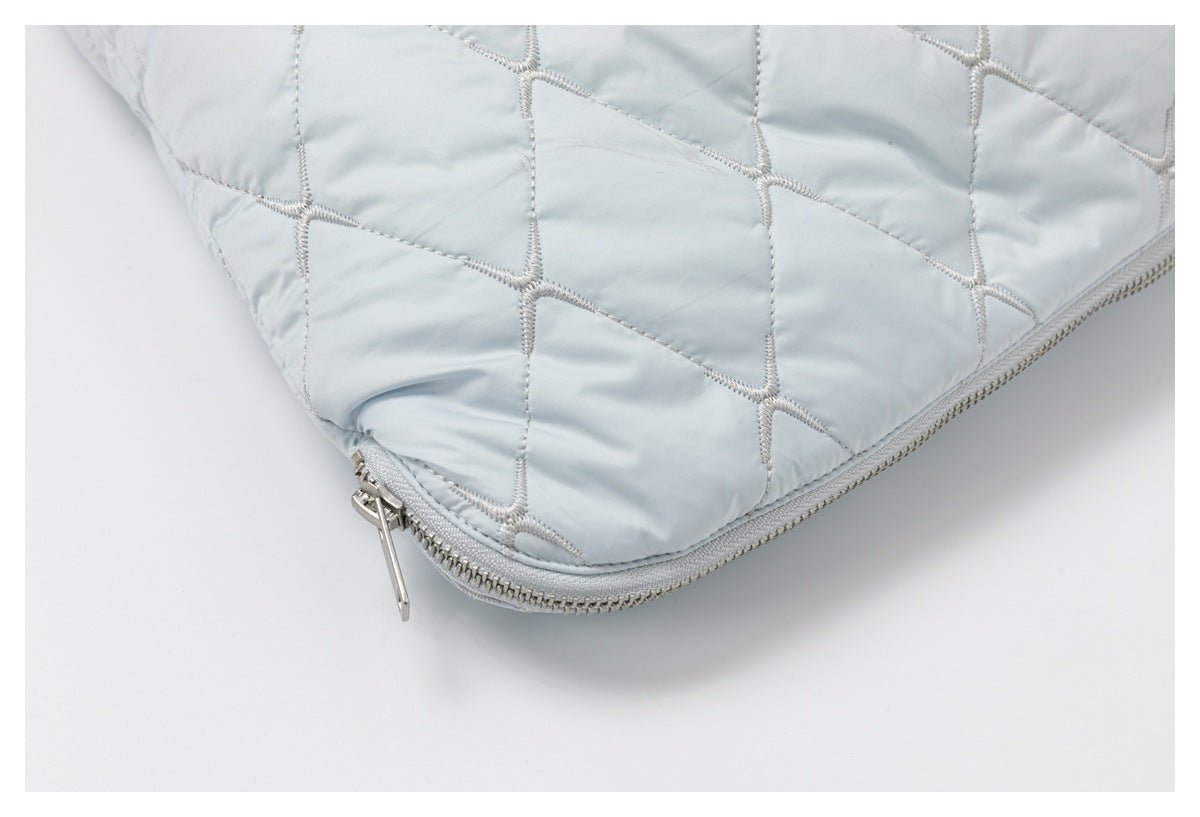 Close-up of the rounded hem and silver zipper on a pale blue quilted garment.