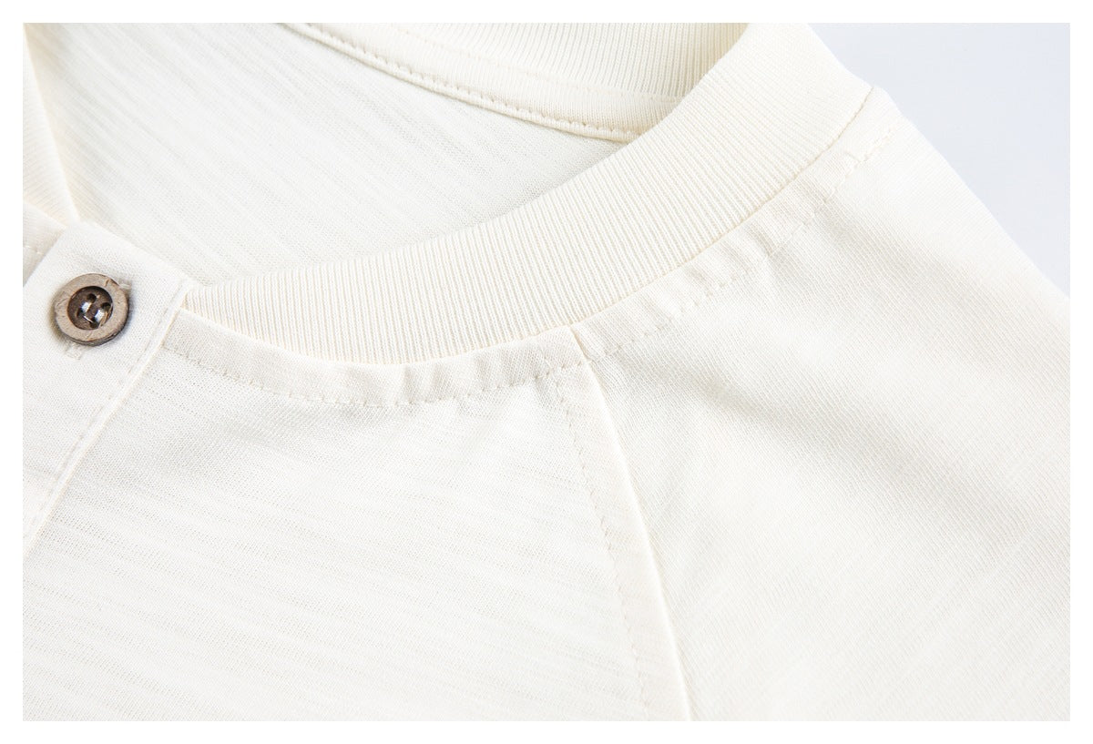 Close-up of an ivory shirt's ribbed crew neckline and raglan shoulder seam.