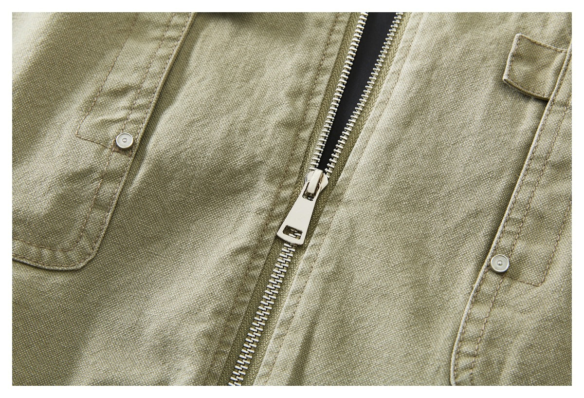 Close-up of an olive khaki jacket's partially open metal zipper and snap-button pocket flaps.