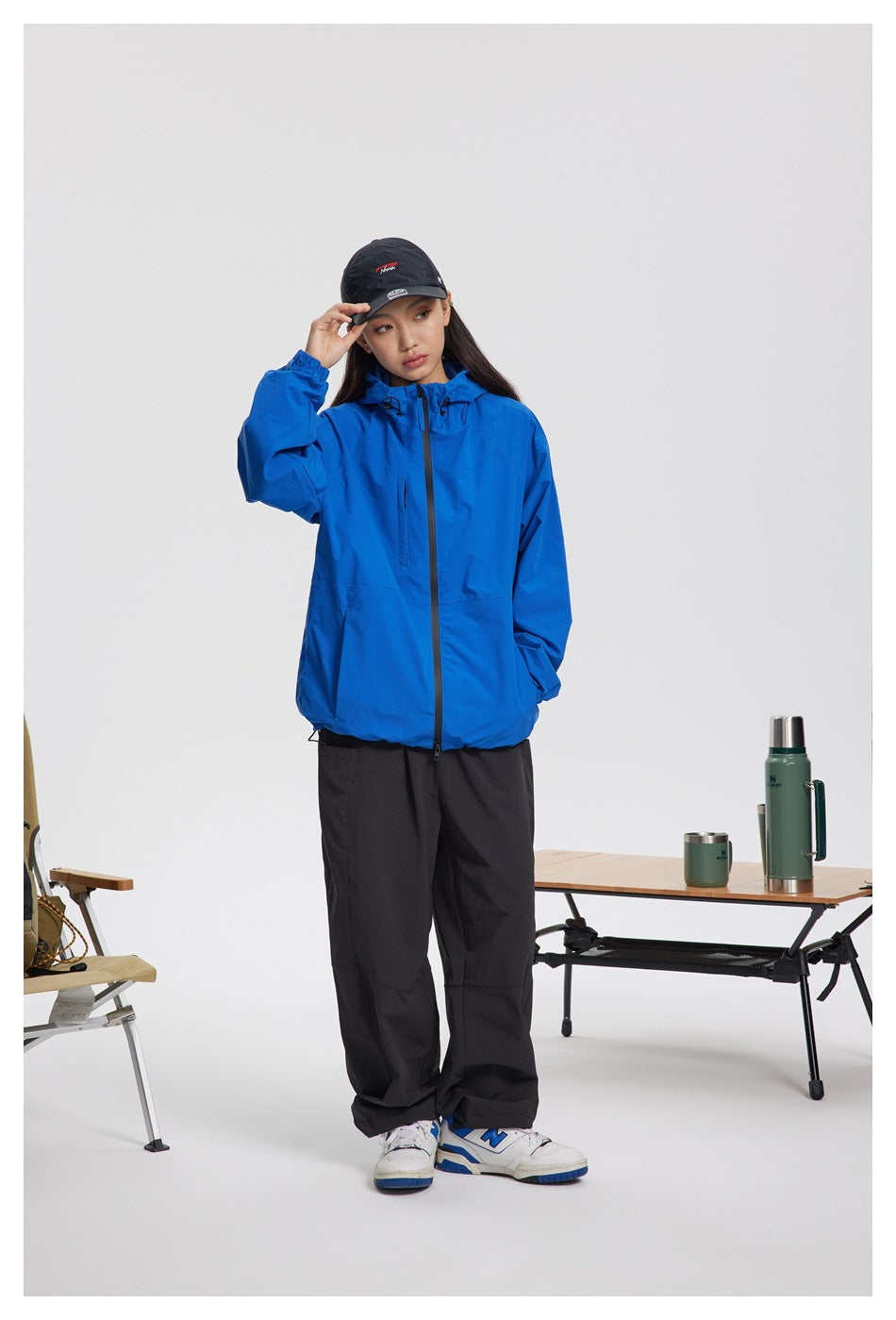 Full-length view of a person wearing a bright blue hooded jacket and black pants.