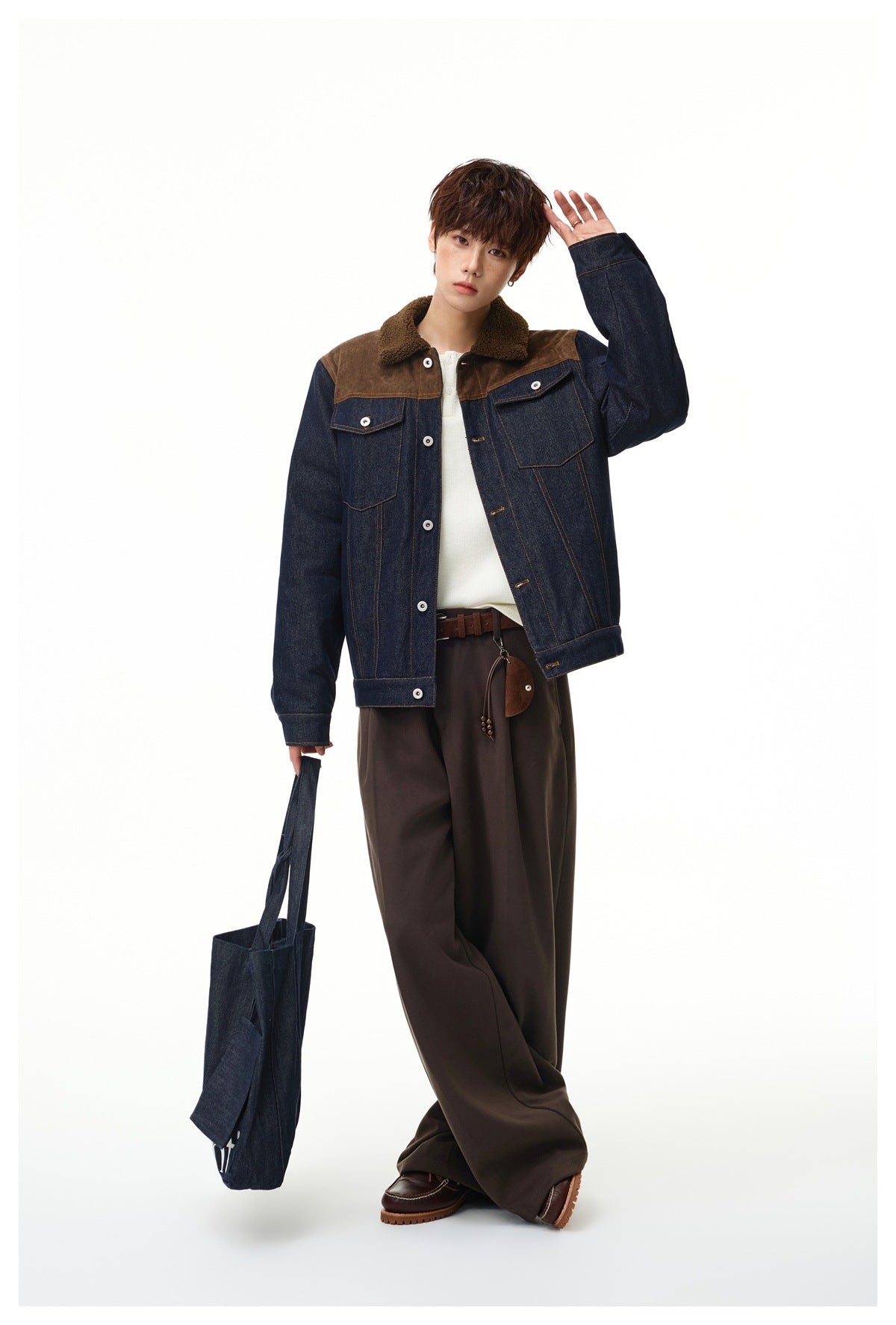 Full-length model wearing a dark denim jacket with brown shoulder panels and sherpa collar, styled with wide trousers.