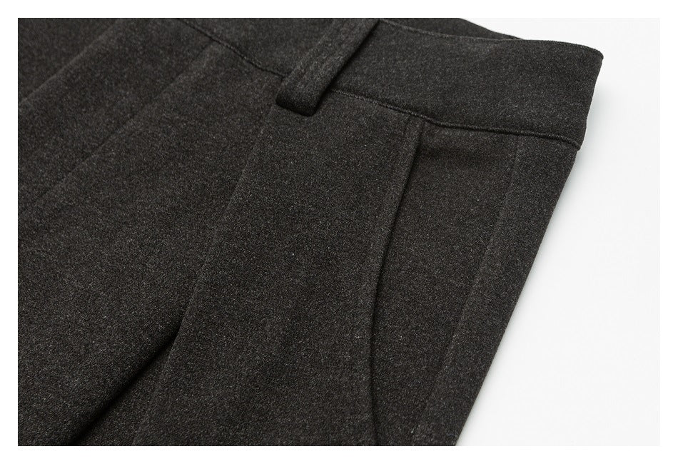 Close-up of charcoal gray trousers showing the waistband, belt loop, and pocket seam.