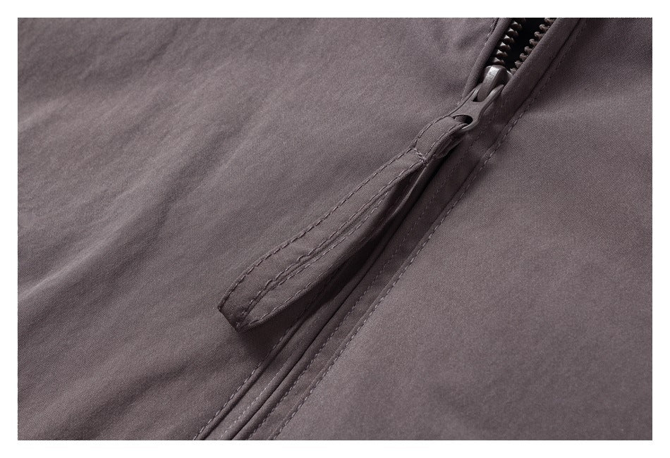 Close-up of the jacket’s front zipper, zipper pull, and stitched placket.