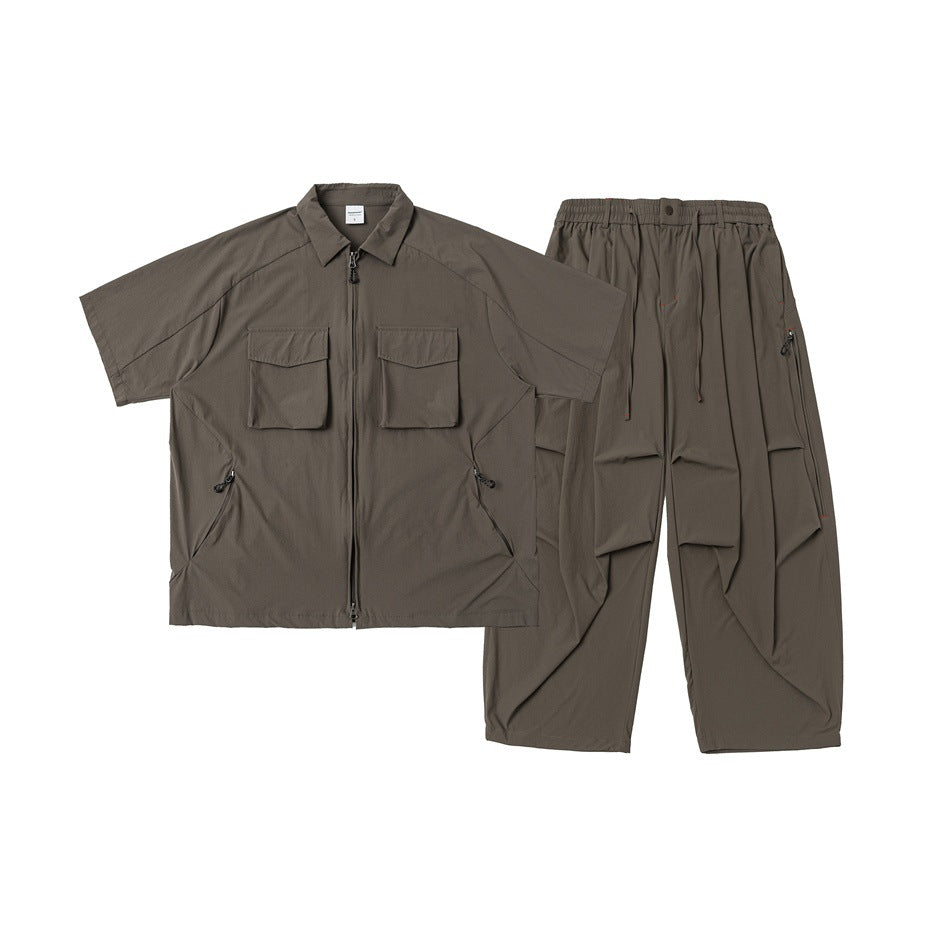 Dark taupe two-piece set laid flat: short-sleeve zip shirt with flap pockets and relaxed drawstring trousers.