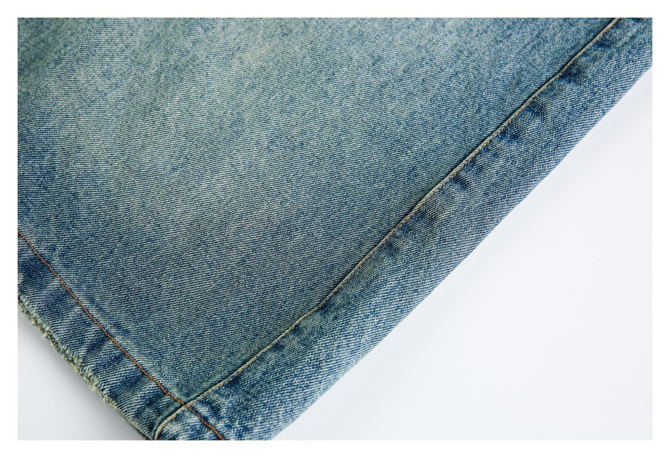 Close-up of a blue washed denim leg and its stitched hem.
