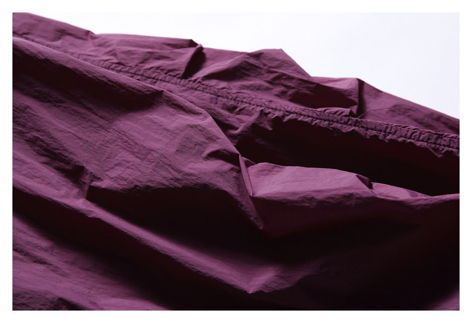 Close-up of a plum jacket's crinkled fabric and stitched seam.
