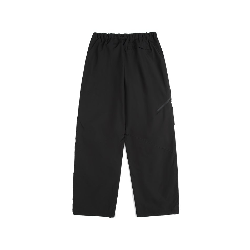 Back view of black loose-fit pants with an elastic waist, small rear pocket, and diagonal leg detail.