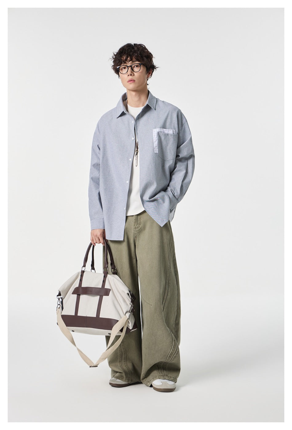 Full-length model wearing a gray button-up shirt with checked chest pocket trim and olive wide-leg pants.