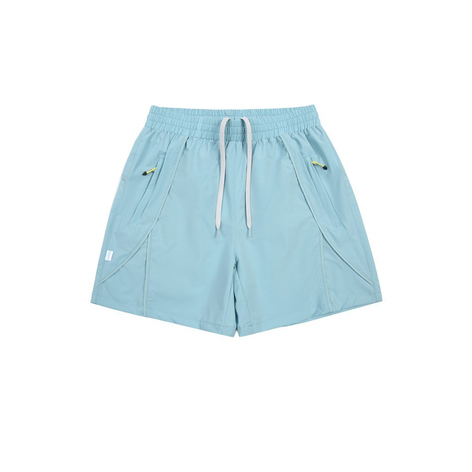 Pale blue athletic shorts with a white drawstring, angled pockets, and small zip pockets with yellow pulls.