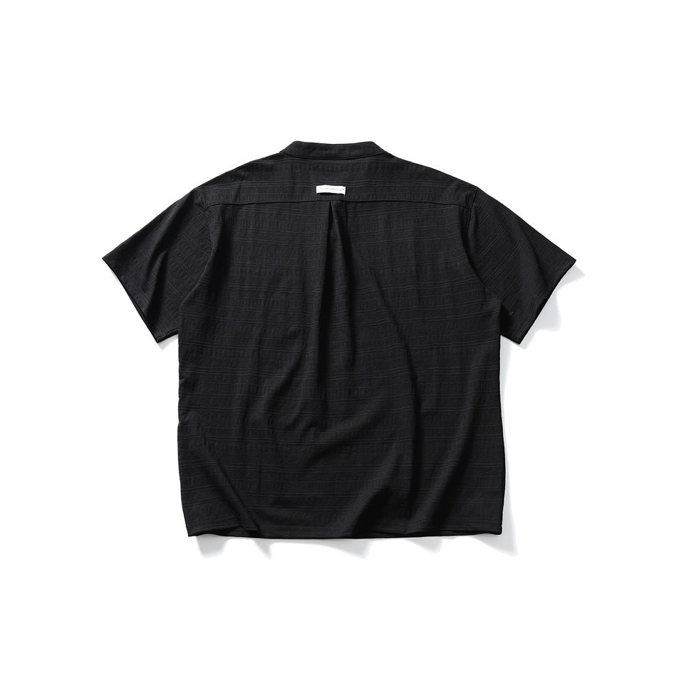 Back view of a black short-sleeve band-collar shirt with subtle horizontal texture and a center pleat.