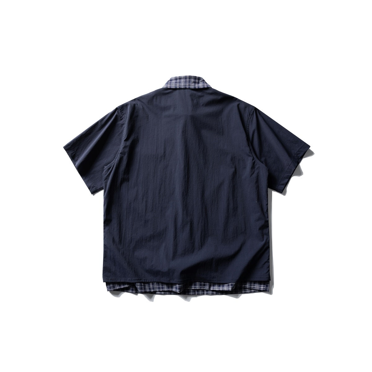 Back view of a navy short-sleeve shirt, with plaid fabric visible at the collar and below the hem.