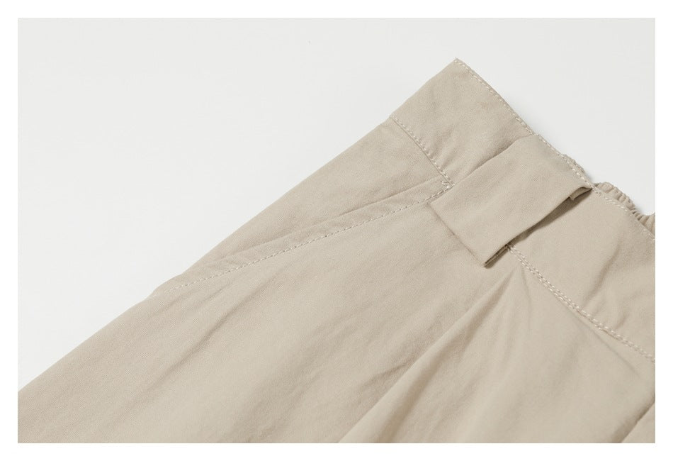 Close-up of beige trousers showing a belt loop and stitched waistband.