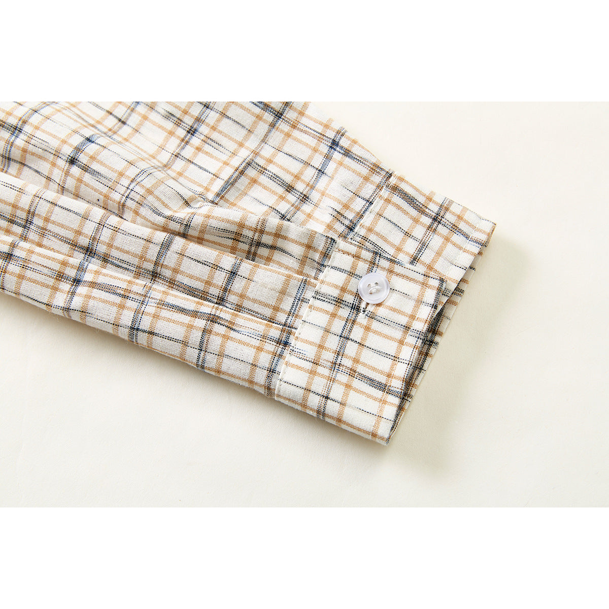 Close-up of the cream plaid shirt sleeve and buttoned cuff.