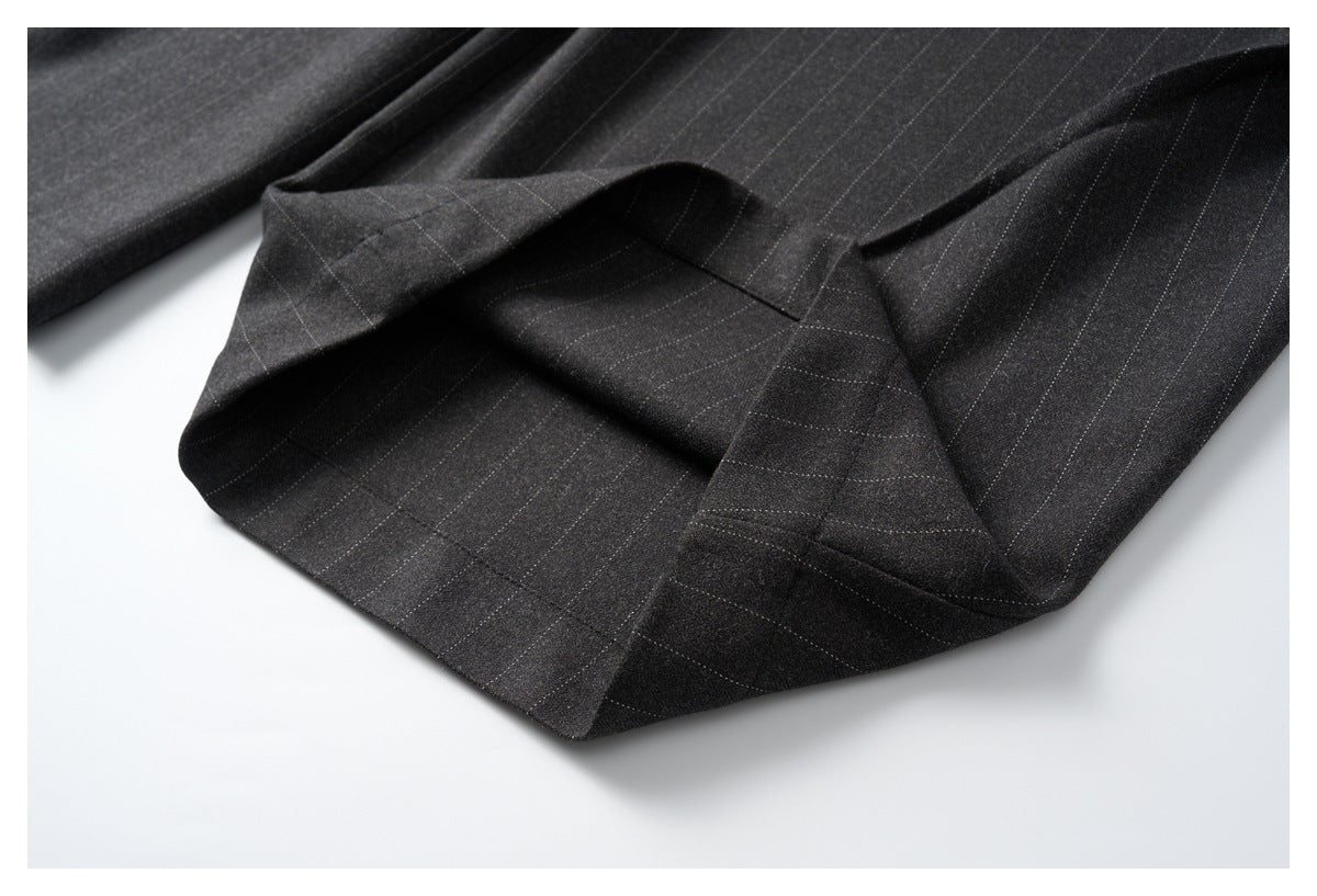 Close-up of a turned-up trouser hem showing the charcoal pinstripe fabric and stitching.