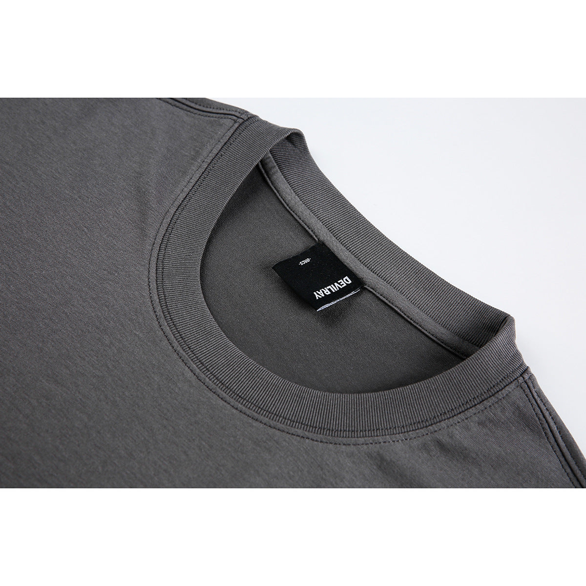Close-up of a charcoal crew-neck garment showing its ribbed neckline and sewn-in black neck label.
